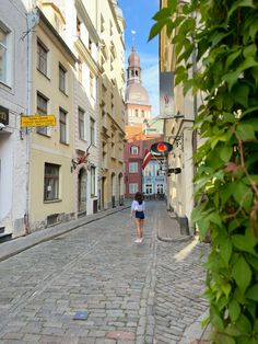 a woman is walking down an old cobblestone street with buildings in the background