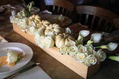 the table is set with white flowers and pumpkins