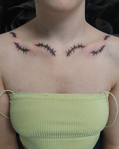 a woman wearing a green top with barbed wire tattoos on her chest and shoulder area