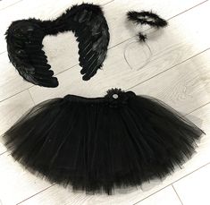 a black tutu skirt and angel wings on a white wooden floor next to a pair of scissors