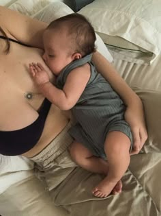 a woman laying on top of a bed holding a baby