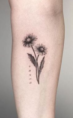 a black and white photo of a sunflower tattoo on the right thigh, with words written below it