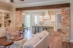 a living room filled with furniture next to a kitchen and dining room table in front of a brick wall