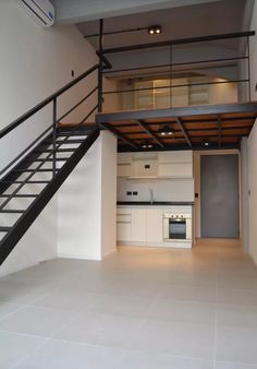 an empty living room with stairs leading up to the kitchen