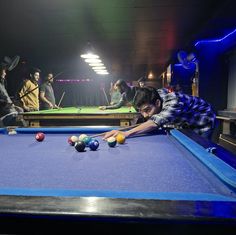 a group of people playing pool in a dark room