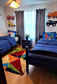 two beds in a room with blue comforters and colorful rugs on the floor