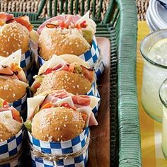 many sandwiches are wrapped in blue and white checkered paper on a tray next to drinks