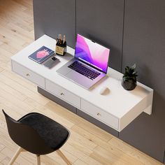 a laptop computer sitting on top of a white desk next to a potted plant