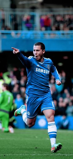 a soccer player is running on the field with his arms out and one foot in the air