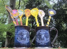 four mugs with spoons in them are sitting on a table near some trees