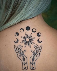 the back of a woman's neck with two hands holding sun and moon tattoos on it