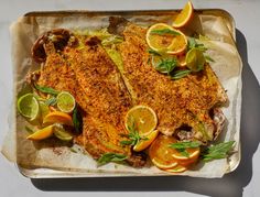 two fish fillets with lemons, oranges and herbs on a baking sheet