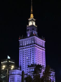 a tall building with a clock tower lit up in the night sky at night time