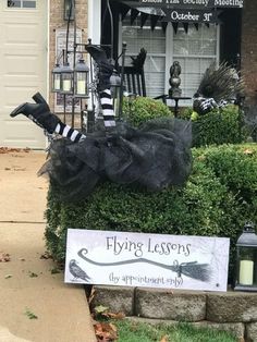 the front yard of a house decorated for halloween with black and white striped stockings, witch brooms and decorations