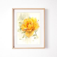 a watercolor painting of a yellow rose in a wooden frame on a white wall