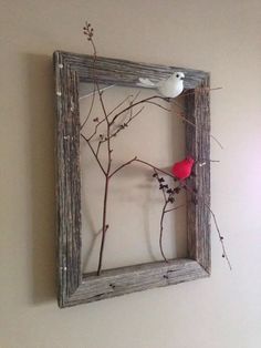 a red bird sitting on top of a branch in a frame with branches and twigs