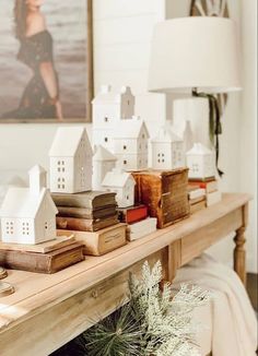 a wooden table topped with lots of books and small white houses on top of it