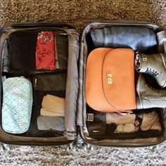 an open suitcase with clothes and shoes inside on the floor next to a carpeted area