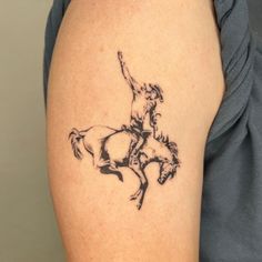 a woman's arm with a tattoo of a horse and rider on the back