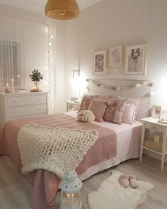 a bedroom decorated in pink and white with lights on the headboard, rugs and bedding