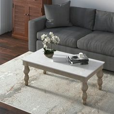 a living room with a gray couch and white coffee table