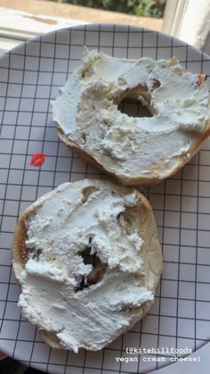 two bagels sitting on top of a white plate covered in cream cheese frosting