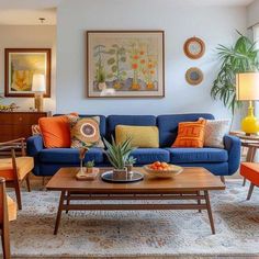 a living room with blue couches and orange pillows on the table in front of it