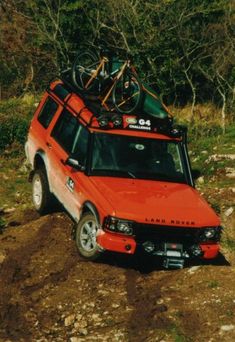 an orange car with bikes on top is stuck in the mud