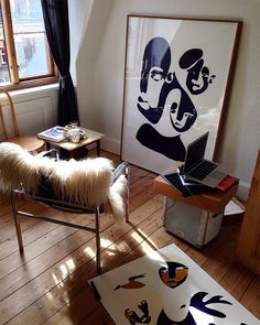 a living room filled with furniture and paintings on the wall next to a chair in front of a window