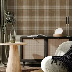 a chair and table in a room with plaid wallpaper on the walls behind it