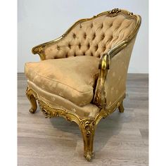 an antique chair with gold paint and upholstered fabric, on a wooden floor