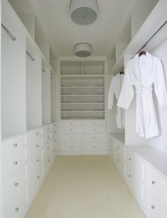 an empty walk - in closet with white cabinets and drawers