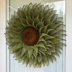 a green wreath hanging on the side of a door with shutters in the background