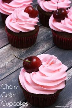 cherry cupcakes with pink frosting and cherries on top, sitting on a wooden table