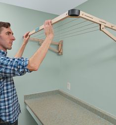 a man is holding the clothesline to hang it on the wall above his head