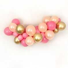 some pink and gold balloons on a white surface with one balloon stuck to the wall