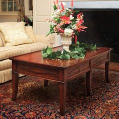 a coffee table with flowers on it in front of a fireplace