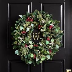 a wreath with the letter v on it is hanging on a black front door,