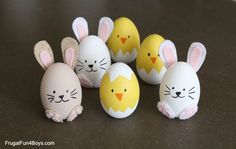 several easter eggs with painted faces in the shape of rabbits and chickens, on a table