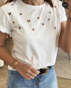 a woman wearing a white shirt with hearts on it and holding a cell phone to her ear