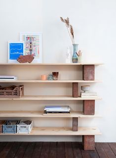 a wooden shelf with books, vases and other items on it in a room