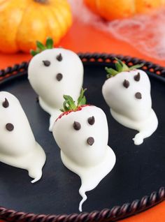 some white chocolate covered strawberries on a black plate