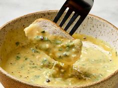 a spoonful of broccoli and cheese soup is being lifted from a bowl