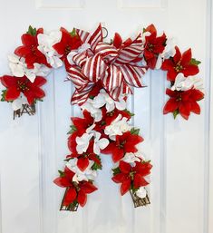 a door decorated with red and white poinsettis, ribbons and bells for the holiday season