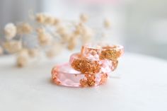 This pink resin ring contains metallic gold flakes suspended in a crystal clear resin. You can wear only one or you can stack two or three rings on a finger. You can also contact me for a custom color request, if you have something else in mind! Width: between 5 mm and 6.5 mm - depending on ring size This listing is for ONE pink resin ring with gold flakes! Handmade by me from scratch, each one of my pieces is hand pigmented, and poured into a silicone mold. After I remove it from the mold I han Pink Resin Ring Jewelry, Handmade Pink Resin Rings, Adjustable Pink Resin Rings, Gold Resin Rings As A Gift, Gold Resin Rings Suitable As A Gift, Gold Resin Rings For Gifts, Gold Resin Rings For Gift, Gold Resin Rings Perfect For Gifts, Dainty Promise Rings