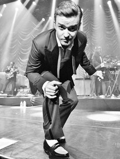 a black and white photo of a man in a tuxedo on the stage