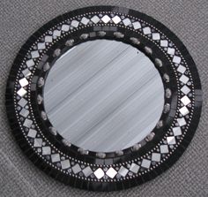 a black and white mirror sitting on top of a gray carpeted floor next to a wall