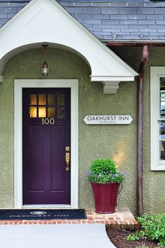 a purple front door on a green house