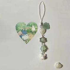 two heart shaped earrings with charms attached to them on a white surface next to an ornament