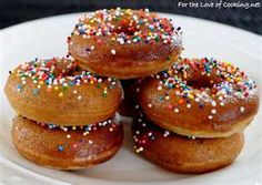 four donuts with sprinkles on a white plate